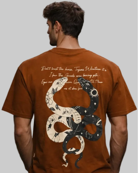 Man wearing a brown t-shirt with a snake design and text on the back, standing in an urban setting.